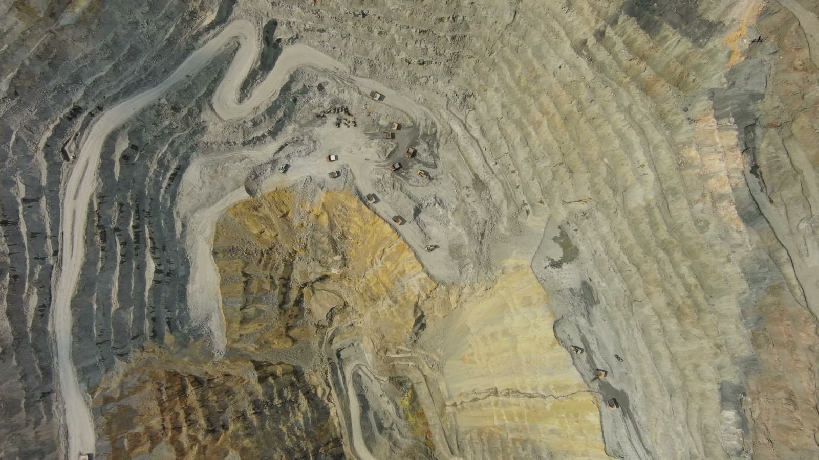 Haul trucks on the benches of an open-pit mine, seen from above